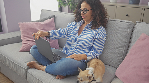 Hispanic woman on her laptop at home with her dog