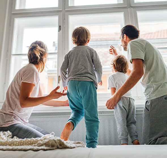 Family on their bed looking out the window.