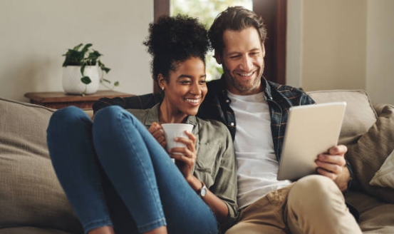 a couple looking at a tablet on their couch